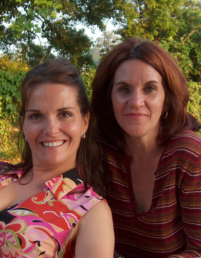 Dos mujeres sonriendo al aire libre con vegetación de fondo, relacionadas con el cuerpo de una mujer desaparecida descubierto en las noticias del garaje.