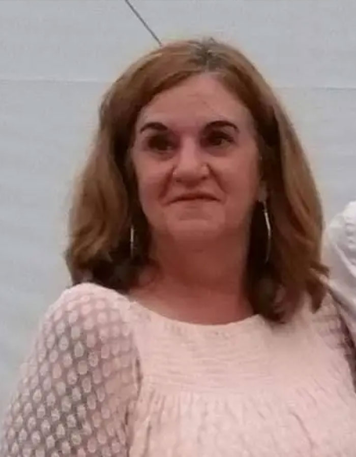 Mujer vinculada al cuerpo de una mujer desaparecida descubierto en una caja de garaje, posando en el interior con una blusa de color claro y aretes de aro.