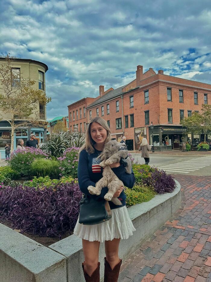 Mujer sosteniendo un conejo grande al aire libre, que ilustra el viaje de Hoppy Gilmore desde un conejo frágil hasta un compañero afectuoso.