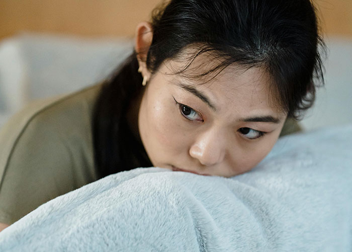 Mujer que parece molesta y sumida en sus pensamientos, reflexionando sobre la traición de su marido a pesar de su apariencia amable y solidaria.