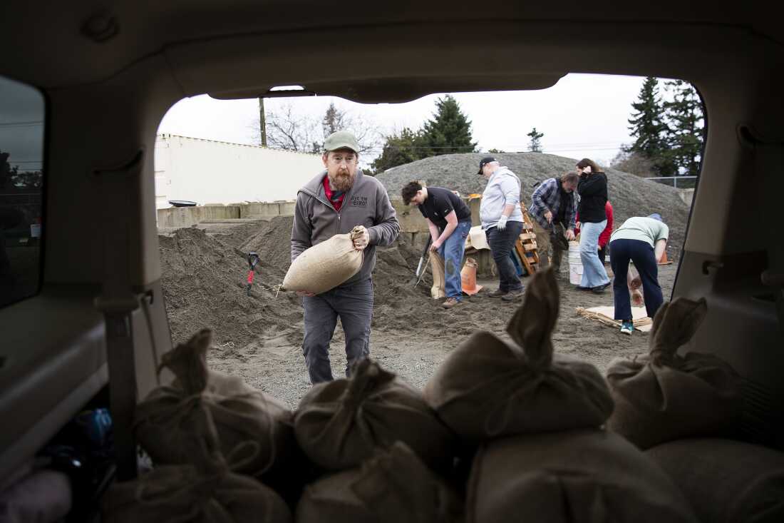 Jason Prescott coloca bolsas de arena llenas en su vehículo en Mount Vernon, Washington, el jueves.