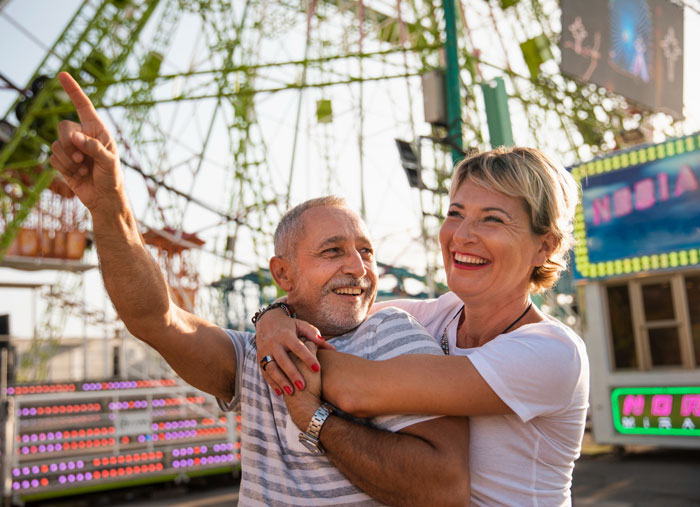 Una pareja sonriente disfrutando de un parque temático, destacando el impacto del sueño de una madre en Disney que causa deuda y culpa en la familia.