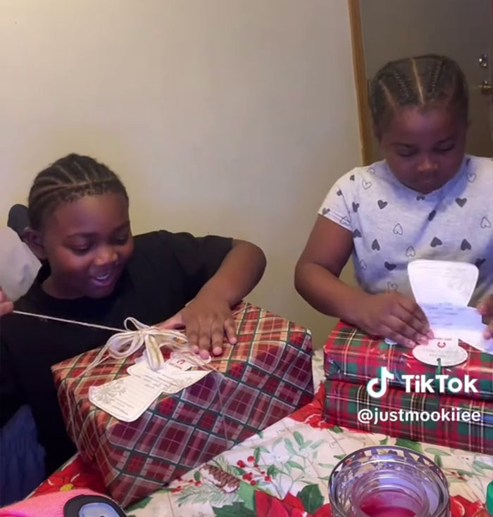 Dos niños abriendo regalos de Angel Tree en una mesa, capturando la reacción de su hijo en un video viral de una madre en TikTok.
