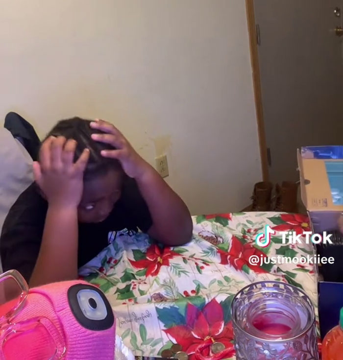 Un niño reacciona a los regalos de Angel Tree en una mesa navideña mientras su madre graba un video viral de TikTok sobre la ingratitud.