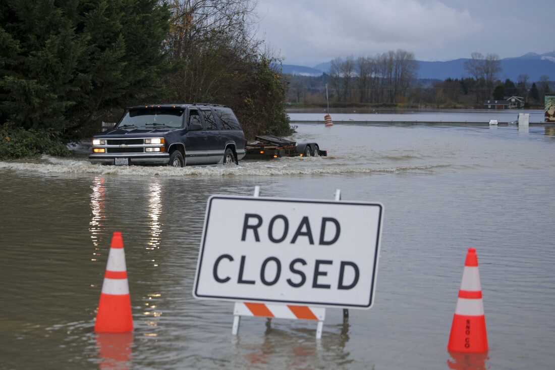 Una persona conduce a través de las aguas inundadas del río Snohomish en Snohomish, Washington, el jueves. Decenas de miles de personas recibieron órdenes de evacuación el jueves en el oeste de América del Norte, después de que días de fuertes lluvias obligaran a los ríos a desbordarse.
