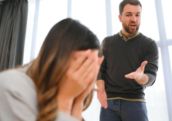 Mujer cubriéndose la cara mientras su novio grita, lo que ilustra señales de alerta en una relación