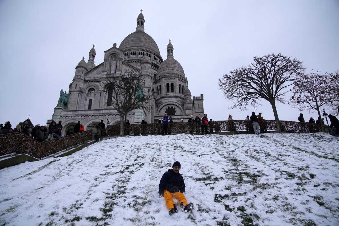 Un hombre juega junto a la nevada Butte Montmartre con la basílica del Sagrado Corazón al fondo, el miércoles 7 de enero de 2026 en París. 