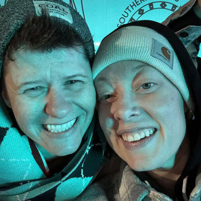 Padre del agente de ICE que mató a Renee Nicole Good fotografiado con una mujer sonriente con gorros de invierno en primer plano.