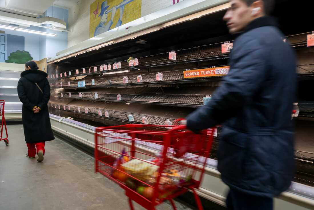 Los compradores pasan junto a estantes casi vacíos en una tienda antes de una tormenta invernal prevista en Nueva York.