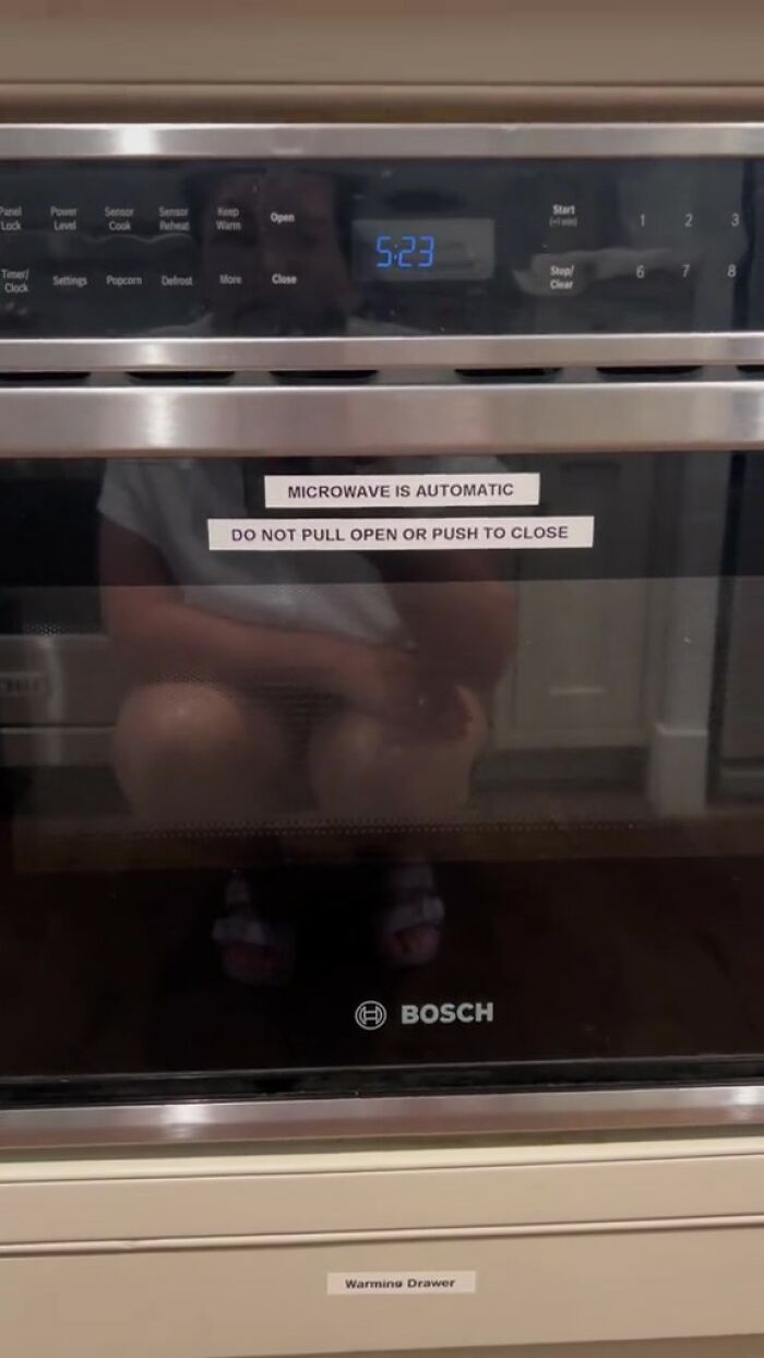 Microondas con pegatina de reglas impresas en una cocina de Airbnb que enfatiza la función automática y las estrictas instrucciones de uso.