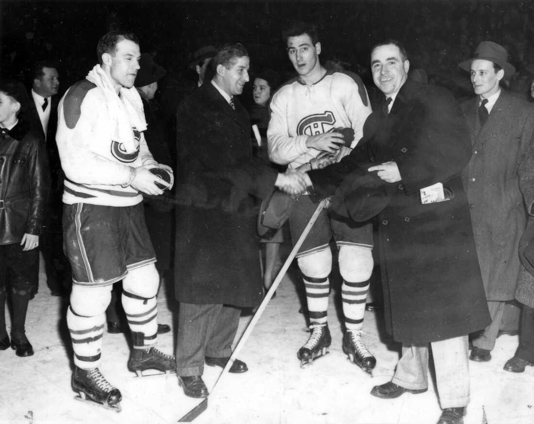 El cofundador de Henri Henri, Jean-Maurice Lefebvre (derecha), le da la mano al entrenador de los Montreal Canadiens, Elmer Lach (i), en la pista del Foro de Montreal, en 1947.