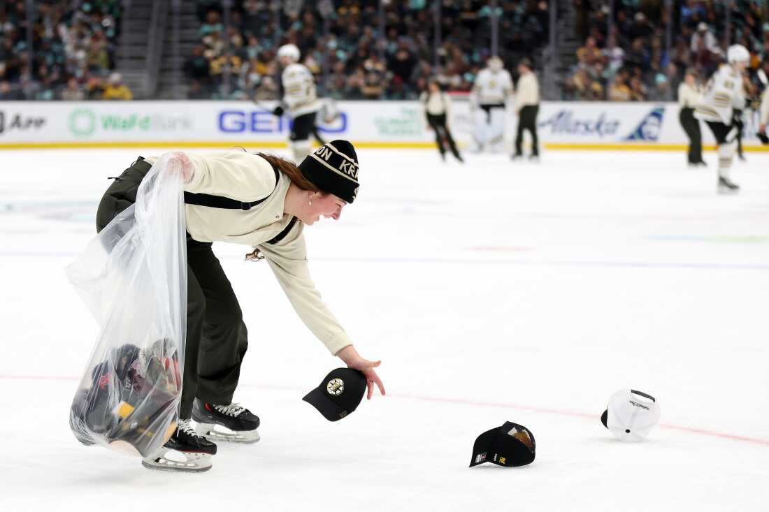 Un miembro de la tripulación de hielo limpia los sombreros del hielo después de un triplete de David Pastrnak #88 de los Boston Bruins durante el tercer período contra el Seattle Kraken en el Climate Pledge Arena el 26 de febrero de 2024 en Seattle, Washington. 