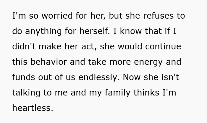 Hermana embarazada sentada sola en un refugio para personas sin hogar, luciendo preocupada y vulnerable en una habitación con poca luz.