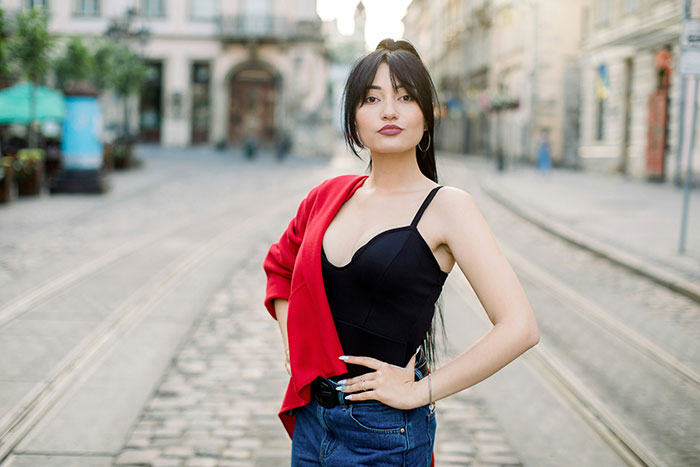 Mujer parada con confianza en una calle de la ciudad, ilustrando los desafíos de los estándares de belleza que afectan a las mujeres de hoy.