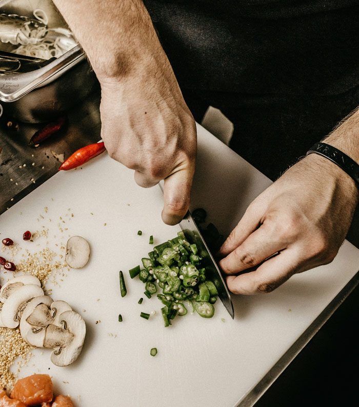 Las manos del hombre cortando verduras en una pizarra blanca que simboliza a un marido que se enfrenta al comentario cruel de su esposa embarazada.