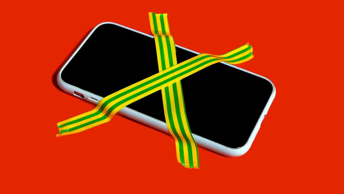 Bodegón colorido de un teléfono inteligente prohibido con cinta adhesiva rayada. 