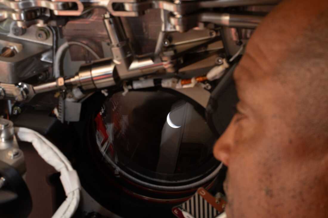 Artemis II pilot and NASA astronaut Victor Glover peers out one of the Orion spacecraft's windows looking back at Earth 