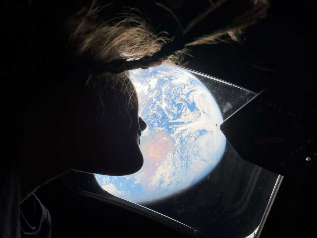  Astronaut and Artemis II mission specialist Christina Koch peers out of one of the Orion spacecraft's main cabin windows, looking back at Earth, as the crew travels towards the Moon.