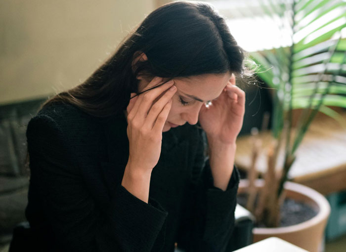 Mujer que enfrenta un dilema, estresada y sumida en sus pensamientos, respecto de que la madre controle su arreglo para dormir con su futura esposa.